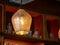 Glass and wire lamp cover on a hanging light bulb in dark bar