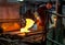 Glass worker mixes molten glass at a glass factory