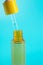 glass yellow bottle with pipette with essential oil on blue background top view. Aromatic cosmetic product for skin hair care