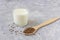Glass of yogurt with flax seeds, wooden spoon with flax seeds on grey background