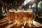 Glasses with amber beer stand on a wooden table in the sun.