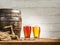 Glasses of beer and ale barrel on the wooden table.