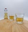 Glasses and bottle of herbal liqueur on wooden table