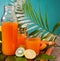 Glasses and bottle of tropical exotic multifruit juice with pineapple and palm leaf on the background