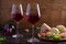 Glasses and bottle of wine with cheese, bread, nuts and jamon or prosciutto on dark wooden background