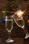 Glasses of champagne with bubbles on the background of Christmas decorations. Two glasses touch each other during a festive toast