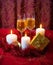 Glasses of champagne, candles, gold gift box and red tinsel