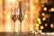 Glasses with champagne and golden ribbons against holiday lights. New Year background. Two glasses of champagne on a table in