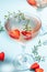 Glasses with cold pink champagne or punch with wine strawberries, ice and rosemary on blue background