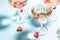 Glasses with cold pink champagne or punch with wine strawberries, ice and rosemary on blue background