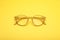 Glasses with corrective lenses on yellow background, top view
