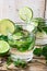 Glasses with detox cucumber water with fresh mint and lime on barn wood box, spring or summer