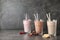 Glasses with different protein shakes and ingredients on table against grey background