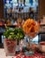 Glasses of dried sliced oranges, mint and rose petals at a bar, with bottles of drinks behind.