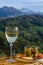 Glasses of dry white wine and spanish tapas olives in bowl with mountains peaks on background in sunny day