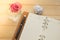 Glasses,empty notebook,pen and pick rose in glass vase on wooden background