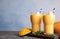 Glasses of fresh mango drink and fruits on table.