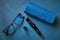 Glasses, glasses case and cleaning handle for optics, on blue background, top view