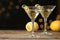 Glasses of Lemon Drop Martini cocktail with zest on wooden table against blurred background