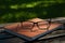 Glasses lie on a leather notebook on a park bench on a sunny day