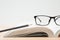 Glasses, open book, pencil on wooden table, white background  and copy space