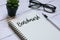 Glasses,plant,pen and notebook written with Benchmark on white wooden background.