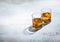 Glasses of single malt finest whiskey with ice cubes on light background