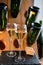 Glasses of sparkling white wine champagne or cava with bubbles and classic wooden champagne pupitre rack with empty bottles on