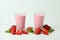 Glasses of strawberry milkshake and ingredients on white background