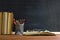 Glasses teacher books and a stand with pencils on the table, on the background of a blackboard with chalk. The concept of the teac