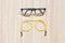 Glasses transparent dark blue frame with yellow eyeglasses strap on a wooden background