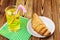 Glassful of lemon soda with ice and tubule on green napkin. croissant, wooden table.