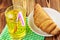 Glassful of lemon soda with ice and tubule on green napkin. croissant, wooden table.