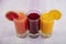 Glassware with refreshing citrus fruits cocktail on white wooden background. Antioxidant juices of Pomegranate Juice, Orange Juice