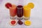 Glassware with refreshing citrus fruits cocktail on white wooden background. Antioxidant juices of Pomegranate Juice, Orange Juice