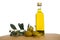 Glassy bottle of olive oil with group of green shiny olives and brunches with leafs