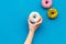 Glazed decorated donut in hand for sweet break on blue background flat lay copy space