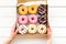 Glazed decorated donuts in box for sweet break on white wooden background flat lay