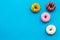 Glazed decorated donuts for sweet break on blue background flat lay copy space