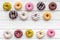Glazed decorated donuts for sweet break on white wooden background flat lay