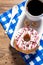 Glazed donut, coffee cup and napkin on wooden background