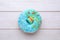 Glazed donut decorated with sprinkles on white wooden table, top view. Tasty confectionery