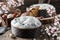 Glazed Easter cake or bread kulich decorated with candy on rustic wooden table with colored easter eggs in basket and spring