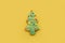 Glazed green Christmas tree cookie with colorful garlands on a yellow background