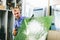 Glazier worker holding a green glass pane in workshop.