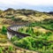 Glenfinnan Viaduct, Scotland. Travel tourist destination in Europe. Old historical steam train riding on film scene famous Harry