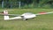 Glider just landed on a green grassy runway with spoilers open