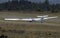 Glider ultralight plane flying near mountains, landing on earth aerodrome