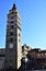 Glimpse of the main square of the city with the bell tower in the foreground that stands in the blue sky in Pistoia near the city