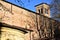 Glimpse of the side and the upper part of the bell tower of the church of the hermits, with the pale moon in the blue sky, seen am